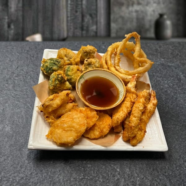 A white rectangular plate filled with various fried foods, including tempura, onion rings, and shrimp.