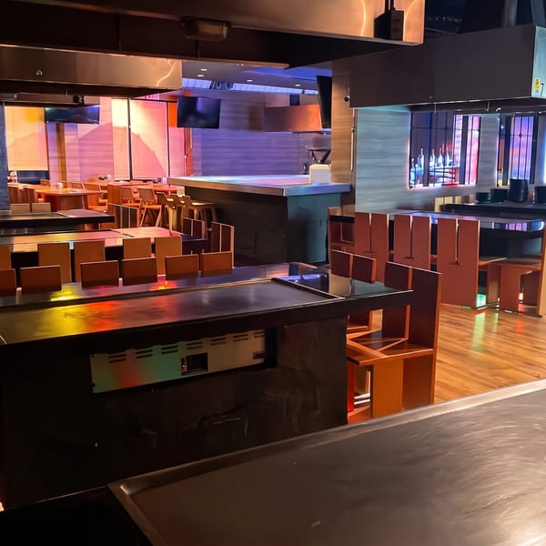 Modern hibachi restaurant interior with multiple cooking stations and colorful ambient lighting.