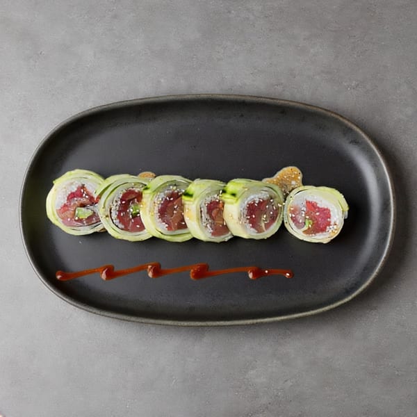 Six pieces of tuna and cucumber sushi rolls with sesame seeds and a drizzle of sauce.