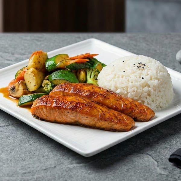 Grilled salmon fillets with steamed vegetables and white rice on a white rectangular plate.